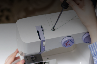 Sewing machine being repaired with screwdriver